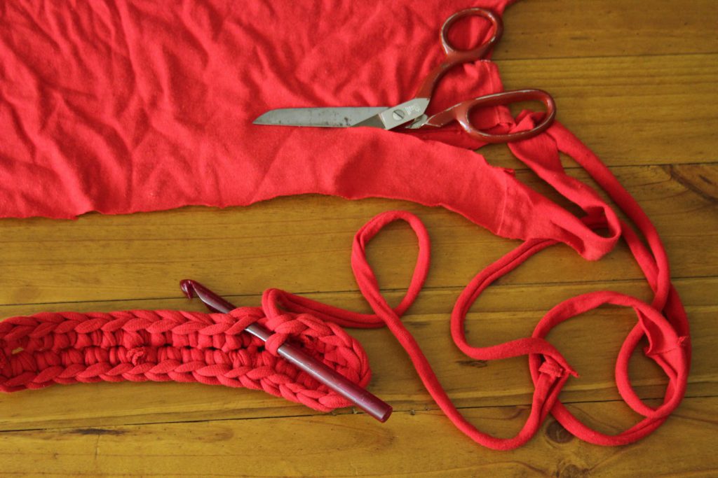 scissors laid looking like its cutting into fabric which unravels into yarn and a crochet hook lays looking likes its crocheting